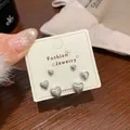 Three pairs of matte gold heart stud earrings in varied sizes on a display card - Heart Jewelry Set / Silver