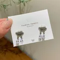 Silver cloud stud earrings with dangling zircon water drops on a white display card - Cloud Drop Earrings / Silver