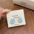 Orecchini a fiore con zirconi blu e perle mostrati su una scheda espositiva - Fiore di Perla Blu Mare