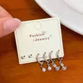 Silver earring set featuring zircon saturn charms and white pearls on jewelry card - Zirconia Wing Style (EKT022)
