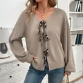 Detailed close-up of oatmeal knit cardigan featuring V-neck and leopard print tie bows - S / Grey Apricot