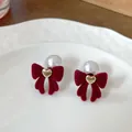 Burgundy velvet bow earrings with pearl and golden heart detail in a ceramic dish - Gold Heart Bow With Pearls