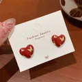 Dunkelrote Herzohrringe mit goldenen Schmetterlingsdetails auf weißer Displaykarte - Schmetterling Herz Stil