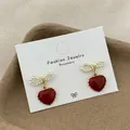 Elegante rote Herzohrringe mit Perlenbogen und goldenem gezacktem Rand auf Karte - Künstliche Perle Schleife Herz Stil