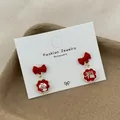 Elegant red bow earrings with lucky gold characters on textured brown ceramic tray - Good Fortune Style