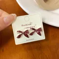 Deep red glitter bow earrings on white card display with sparkling finish for women - Christmas Red Bow Style
