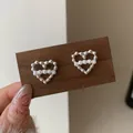 Elegante silberne Herz-Ohrstecker mit vier weißen Perlen auf einem Display präsentiert - Gedrehtes Herz-Design mit Perlen (CF3)