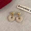 Eleganti orecchini a cuore floccati beige con metallo dorato testurizzato e stile vintage francese - Orecchini Cuore Beige