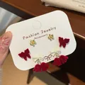 Three-piece red flocked bow and flower earring set on white display card - Red Lily of the Valley