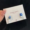 Orecchini asimmetrici con orsetto blu e galassia con stelle d'argento su carta bianca - Orecchini Orso Pianeta Asimmetrici / Orso Blu Pianeta (XK1)