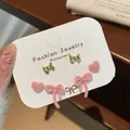 Three pairs of sweet pink flocked bow and heart stud earrings on a display card - Pink Bowknot