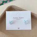 Light blue fabric bow earrings with sparkling heart-shaped zircon drop on display card - Blue Zirconia Bowtie