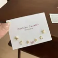Three-pair gold earring set with cross, moon, and flower designs on display card - Gold Four-Leaf Clover Set (JTZT010)