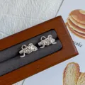 Silver croissant stud earrings with bow details displayed in a luxury wooden gift box - Croissant Bowknot