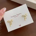 Elegant gold bow earrings with a central sparkling zircon on a white display card - Golden Tie Bowknot