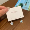 Star-shaped earrings with iridescent blue inlay on a silver card holder - Dazzling Blue Star Ear Buckle