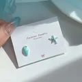 Asymmetric light blue starfish and seashell stud earrings on a jewelry display card - Blue Starfish Conch