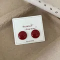 Retro deep red round stud earrings with glossy finish on a jewelry display card - Ancora Red Round Stud (REW5)