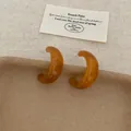 Amber resin C-shaped hoop earrings with retro brown tortoiseshell texture on beige fabric - Crescent Amber C Ring