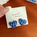 Blue plaid fabric heart stud earrings on decorative card against wooden background - Blue White Plaid Heart