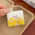 Handmade yellow fuzzy star earrings with silver bow detail on display card - Yellow Bow Star