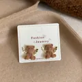 Cute brown flocked bear stud earrings with golden angel wings on a jewelry card - Angel Bear / Brown