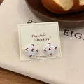 Vintage red heart square stud earrings on white card over natural beige fabric - Square Stud Earrings / White