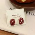 Vintage dark red oval heart stud earrings with geometric pattern on display card - Arch Stud Earrings / Red