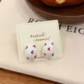 Vintage white oval stud earrings featuring red heart patterns on cream card display - Arch Stud Earrings / White