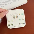 7-pair golden stud earring set featuring panda and green flower designs on card - Panda Bead