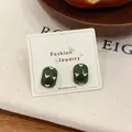 Vintage dark green oval stud earrings with white heart patterns on display card - Arch Stud Earrings / Green
