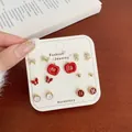 Golden stud earring set with red apples, butterflies, and pearls on display card - Button Apple Pattern