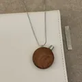 Detailed close-up of a vintage wood perfume bottle pendant on a sleek snake chain necklace - Coffee Round Necklace