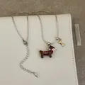 Détail du collier teckel en émail rouge avec un petit pendentif en forme d'os doré - Collier Teckel