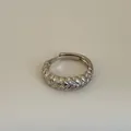 Detailaufnahme des geflochtenen Silberrings mit Zirkonia-Steinen auf beigem Grund - Geflochtener Kleiner Zirkonia-Offen-Stil (Kuan 11 Ring)