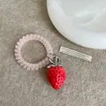 Nahaufnahme eines rosa Spiralgummis mit einem detaillierten Erdbeeranhänger auf Filz - spiralförmige Haargummis