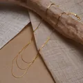 Détail d'un collier triple couche doré avec chaînes fines et breloque cœur - Style Superposé à Trois Rangs / Or