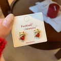 Golden fortune cat stud earrings with red bead accent on white jewelry card display - Dancing Maneki Neko Style (ZCM2)