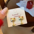 Festive golden fortune cat earrings with red accents and bell pendants on white card - Maneki Neko With Bell Pendant Style (ZCM5)