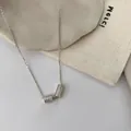 Vue macro détaillée des pendentifs cylindriques en argent S925 avec zircons sur chaîne fine - Or