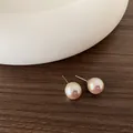 Dettaglio di orecchini a perno con perle tonde dal lustro rosa su superficie in legno - Stile Perla di Conchiglia (Y-0308) / 12mm