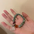Close-up of beaded bracelet with green stones and a pink lotus pod charm detail - Lotus Seed Pod Pendant Style / Coffee Red Resin Bracelet Gold Plated