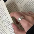 Close-up of irregular silver starburst ring worn on index finger over vintage book pages - Silver (Large Star Ring Gold Plated)