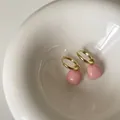 Detailansicht goldener Creolen mit eleganten rosa quadratischen Emaille-Anhängern - Rosa