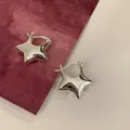 Primer plano de pendientes de aro con estrella plateada y acabado pulido minimalista - Plateado