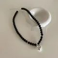 Detailed view of black beaded necklace featuring a polished silver heart pendant and lobster clasp - Large Heart Style