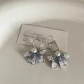Elegant blue gradient floral stud earrings with pearls and crystal accents on a white tray - Zirconia Bow