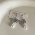 Detailed macro view of blue gradient crystal bow earrings with white pearl drops - Long Bowknot Style