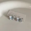 Close-up of blue gradient crystal butterfly earrings on a minimalist display card - Crystal Butterfly Style