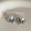 Macro shot of blue gradient crystal flower earrings with a centered white pearl - Pearl Bowknot Style